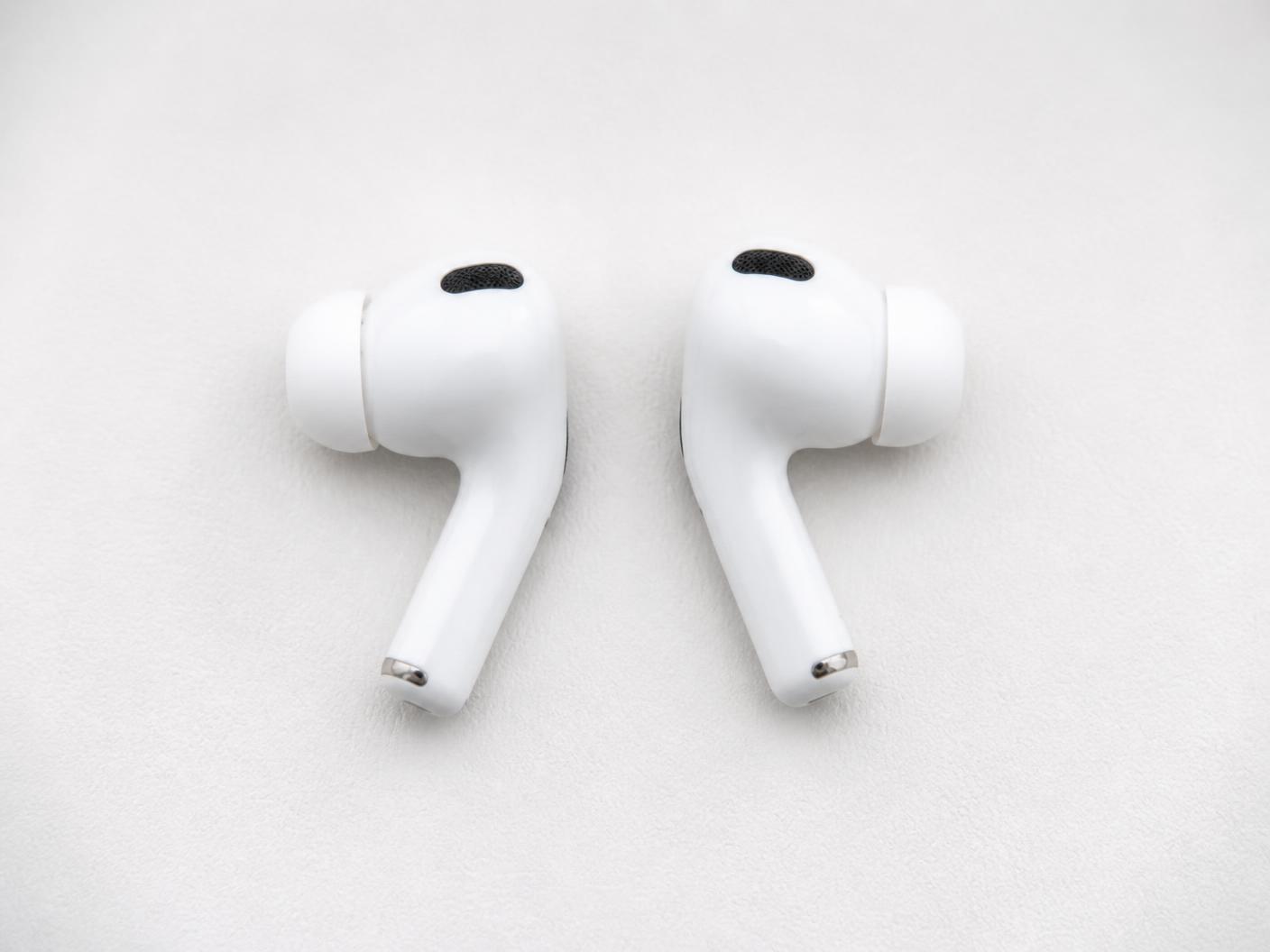 A pair of AirPods Pro earbuds resting on a soft off-white surface